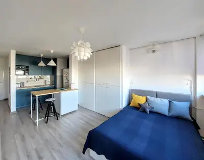 a bedroom with a blue bed and a kitchen at Cozy studio apartment in Belgrade