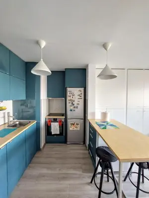 a kitchen with blue cabinets and a stainless steel refrigerator at Cozy studio apartment in Belgrade