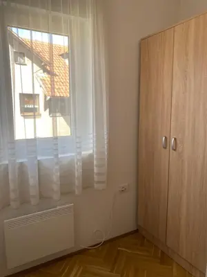 a white room with a window and a wooden cabinet at Apartman Ljubica in Arandjelovac