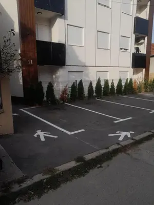 a parking lot with white arrows in front of a building at Apartman Ana in Kumodraž
