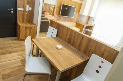 a dining room with a wooden table and white chairs at Apartment Barcelona in Belgrade
