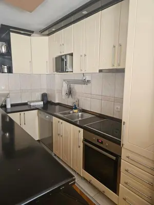 a kitchen with white cabinets and a black counter top at Apartman Cvijetinovic in Ruma