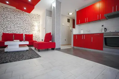 a kitchen with red cabinets and a red couch and chair at Apartment Red in Belgrade