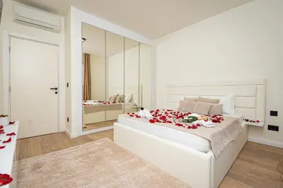 a white bedroom with a large bed and a mirror at Sinfonia Lux 1205 in Sajmište
