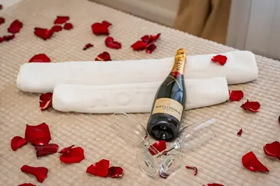 a bottle of wine and red roses on a bed at Sinfonia Lux 1205 in Sajmište