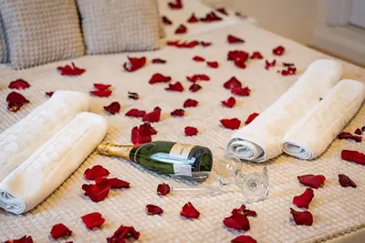 a bottle of wine and red flowers on a bed at Sinfonia Lux 1205 in Sajmište