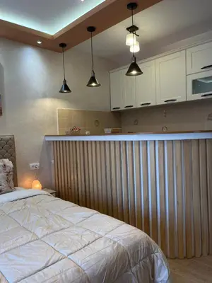 a bedroom with a bed and a kitchen with white cabinets at ANDREA in Mali Mokri Lug