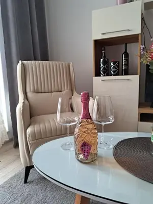 a table with two wine glasses and a bottle on it at Apartman Bross in Ruma