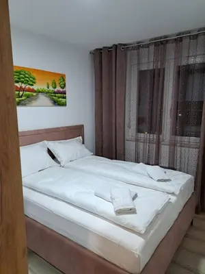 a bedroom with a large bed with white sheets at Apartman Bross in Ruma