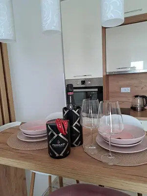 a table with two wine glasses and plates on it at Apartman Bross in Ruma