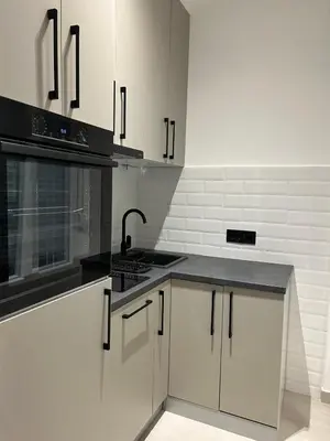 a kitchen with white cabinets and a black counter top at KaLuMa2 in Belgrade