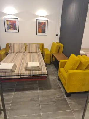a room with a bed and two yellow chairs at Runaway Hill in Bežanija