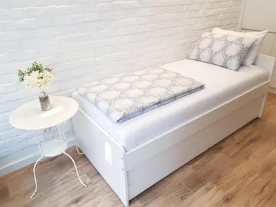a white bed in a room with a side table at VeryBell in Belgrade