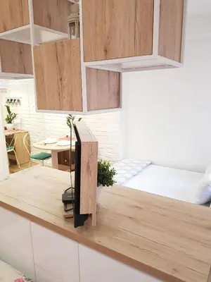 a kitchen with wooden cabinets and a bed on a counter at VeryBell in Belgrade