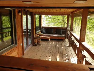 an open porch of a cabin with benches and windows at Log cabin in Belgrade