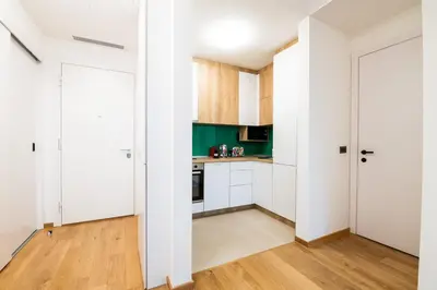 a kitchen with white cabinets and wooden floors at City Center - Sunrise Apartment with Parking in Belgrade
