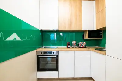 a kitchen with white cabinets and green walls at City Center - Sunrise Apartment with Parking in Belgrade