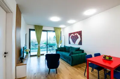 a living room with a green couch and a red table at City Center - Sunrise Apartment with Parking in Belgrade