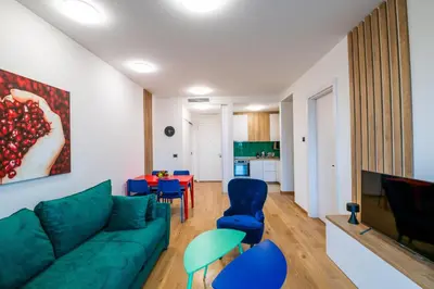 a living room with a green couch and blue chairs at City Center - Sunrise Apartment with Parking in Belgrade