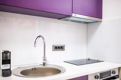 a kitchen counter with a sink and purple cabinets at City Center - Colors Apartment with Garage in Belgrade