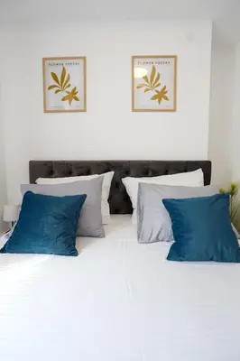 a white bed with blue pillows on top of it at DreamLand Apartment in Surčin