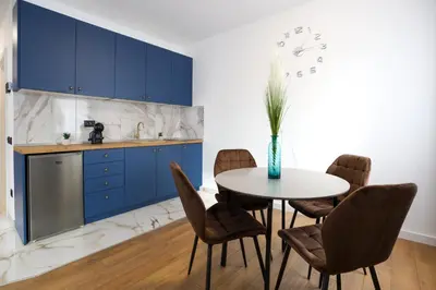 a kitchen with blue cabinets and a table with chairs at DreamLand Apartment in Surčin