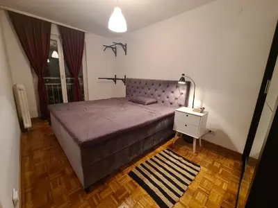 a bedroom with a large bed and a night stand at 70 square meters in Block 61 in Bežanija