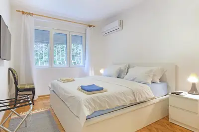 a white bedroom with a bed and a chair at The 7 Apartment - Modern Flat with Terrace near Parliament, Belgrade Center in Belgrade