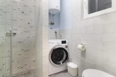 a bathroom with a washing machine and a toilet at The 7 Apartment - Modern Flat with Terrace near Parliament, Belgrade Center in Belgrade