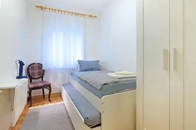 a small bedroom with a bed and a chair at The 7 Apartment - Modern Flat with Terrace near Parliament, Belgrade Center in Belgrade