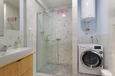 a bathroom with a shower and a washing machine at The 7 Apartment - Modern Flat with Terrace near Parliament, Belgrade Center in Belgrade