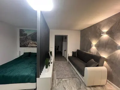 a bedroom with a green bed and a couch at Agate Apartment in Belgrade