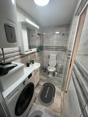 a bathroom with a washer and a toilet and a sink at Agate Apartment in Belgrade