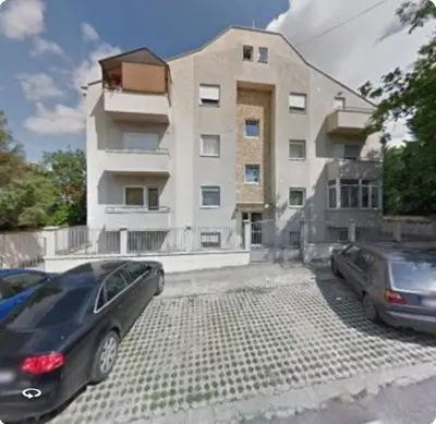 two cars parked in front of a building at Dina cozy apartment in Zemun
