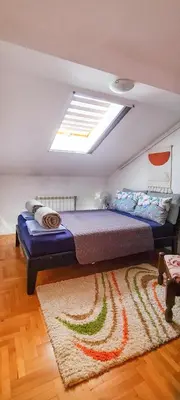 a bedroom with a large bed with a rug at Dina cozy apartment in Zemun