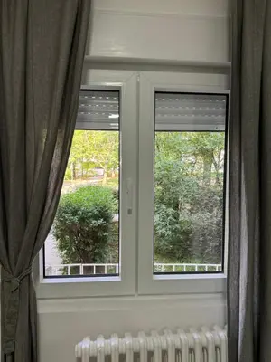 two windows in a room with curtains and a radiator at Sixty three in Novi Beograd