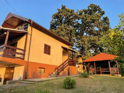 an orange building with a porch and a tree at Vila Plavinac in Smederevo