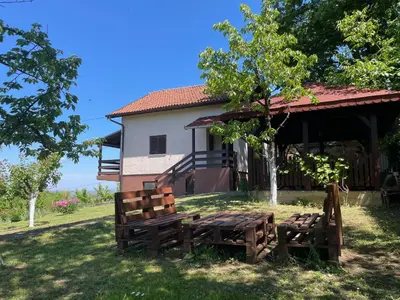 a house with two wooden benches in the yard at Vila Plavinac in Smederevo