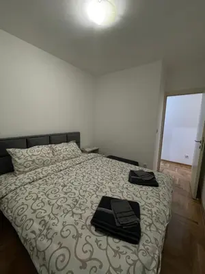 a bedroom with a bed with two black towels on it at Cvetanov trg LUX 4 in Belgrade