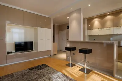 a kitchen with white cabinets and a flat screen tv at Apart K Apartments in Belgrade