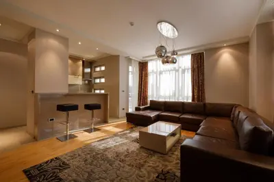 a living room with a brown couch and a kitchen at Apart K Apartments in Belgrade