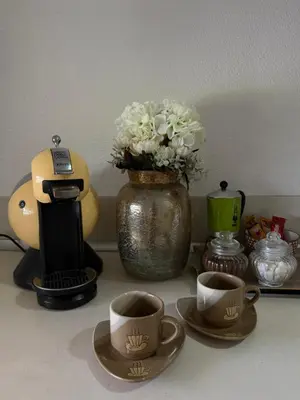 a table with cups of coffee and a vase with flowers at Beli Dvor na Dunavu in Kovin