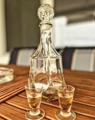 a glass bottle sitting on a table with two glasses at Beli Dvor na Dunavu in Kovin