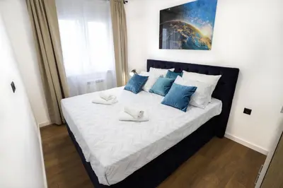 a large bed with blue pillows in a bedroom at Tesla Sky Apartment in Ledine