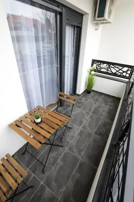 a balcony with two wooden chairs and a table at Tesla Sky Apartment in Ledine