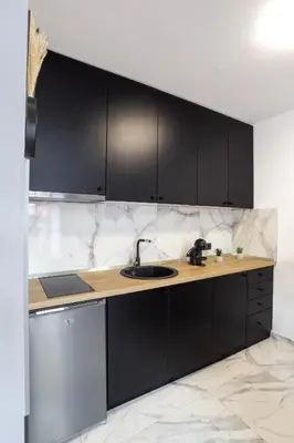 a kitchen with black cabinets and a sink at Tesla Sky Apartment in Ledine