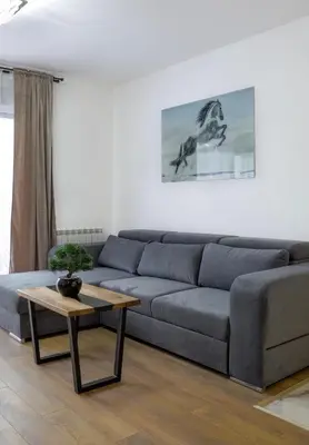 a living room with a blue couch and a table at Tesla Sky Apartment in Ledine