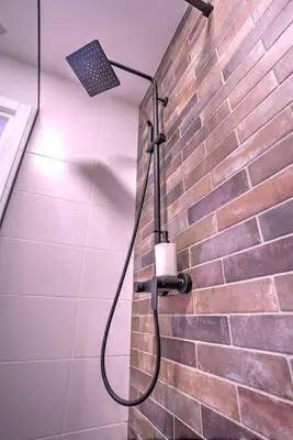 a shower in a bathroom with a brick wall at Belgrade Central Apartment in Belgrade