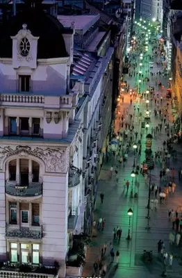 a city street at night with a clock on a building at Belgrade Central Apartment in Belgrade