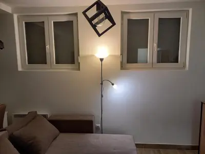 a living room with a couch and two windows at Apartman DUDA Surčin in Surčin